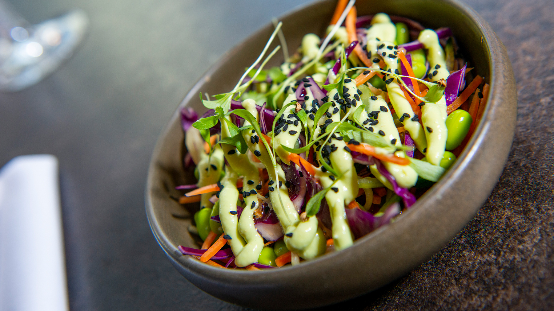 Rainbow salad in a bowl with sesame seeds.