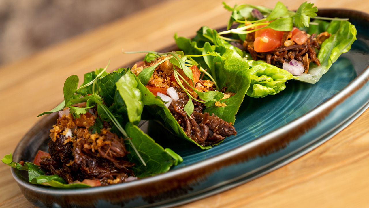 Three ox cheek tacos served in lettuce leaves.